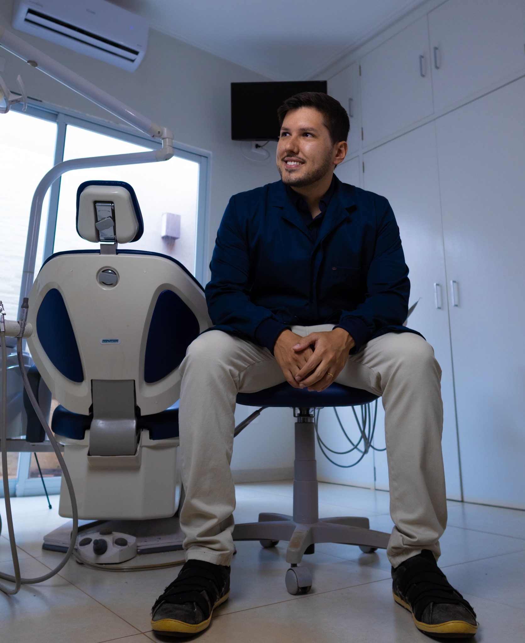 Dr. Murilo Bomfim Alves de braços cruzados no consultório da Odontologia Alves